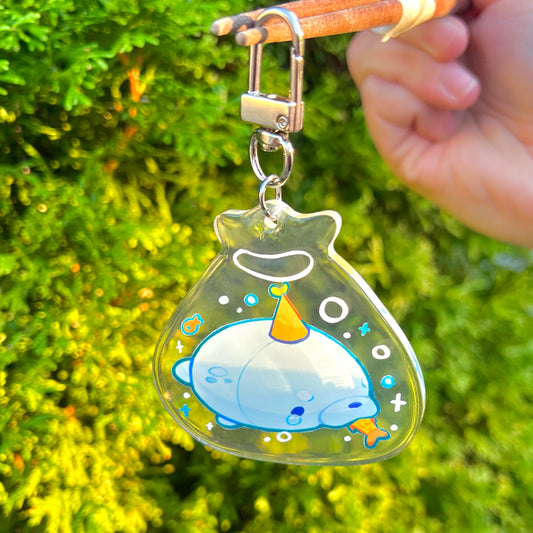 Keychain with cartoon seal held against a green leafy background